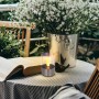 Lampada da tavolo solare a LED Globo con effetto fuoco in acciaio inox su tavolo con libro e vaso di fiori.