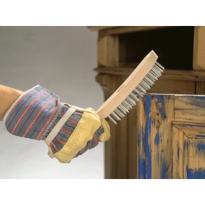 Mano con guanto che utilizza spazzola metallica LUX (a 4 file) per rimuovere la ruggine dal legno.