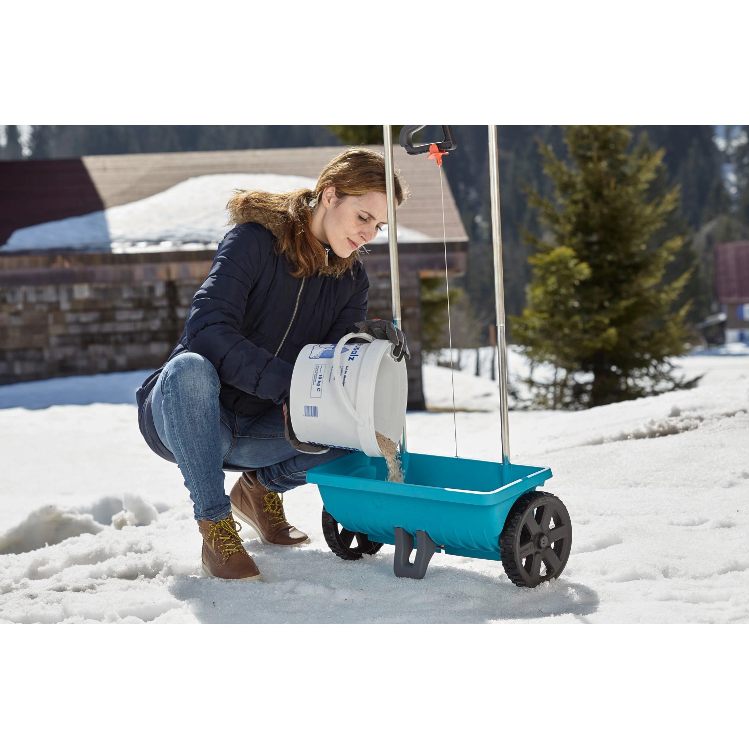 Donna riempie lo spargitore Gardena L con fertilizzante o sale in inverno.