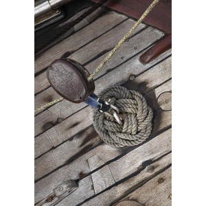 Dettaglio di cordame e bozzello su un ponte di legno. Accessori nautici.