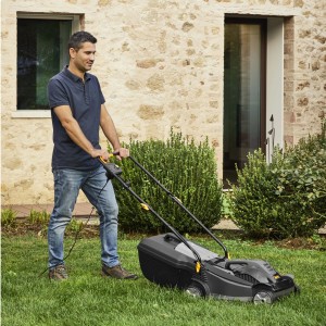 Uomo che utilizza un tosaerba elettrico t.b.t. nero in giardino.