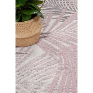 Dettaglio di un tappeto da esterno rosa e bianco con motivo a foglie di palma.