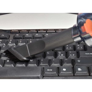 Accessorio per aspirapolvere con spazzola che pulisce una tastiera nera del computer. Cura dell'auto.